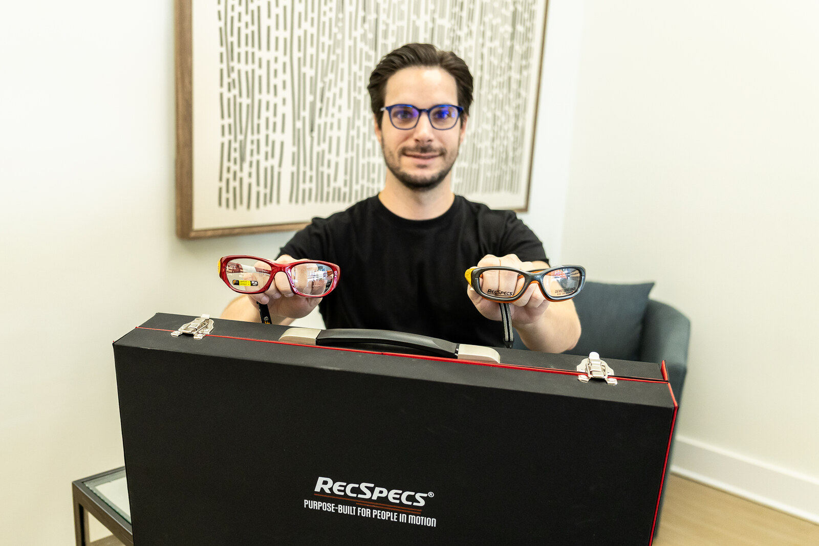 An Ardmore Eye & Optical team member presenting two colorful Rec Specs sports frames