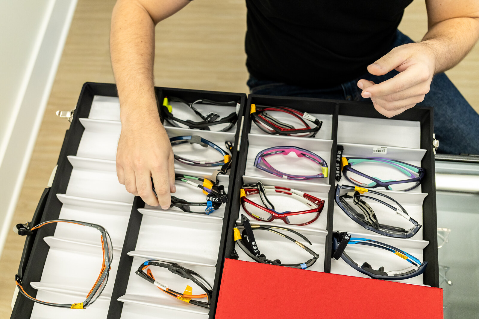 An Ardmore Eye & Optical team member selecting colorful Rec Specs sports frames from a display tray